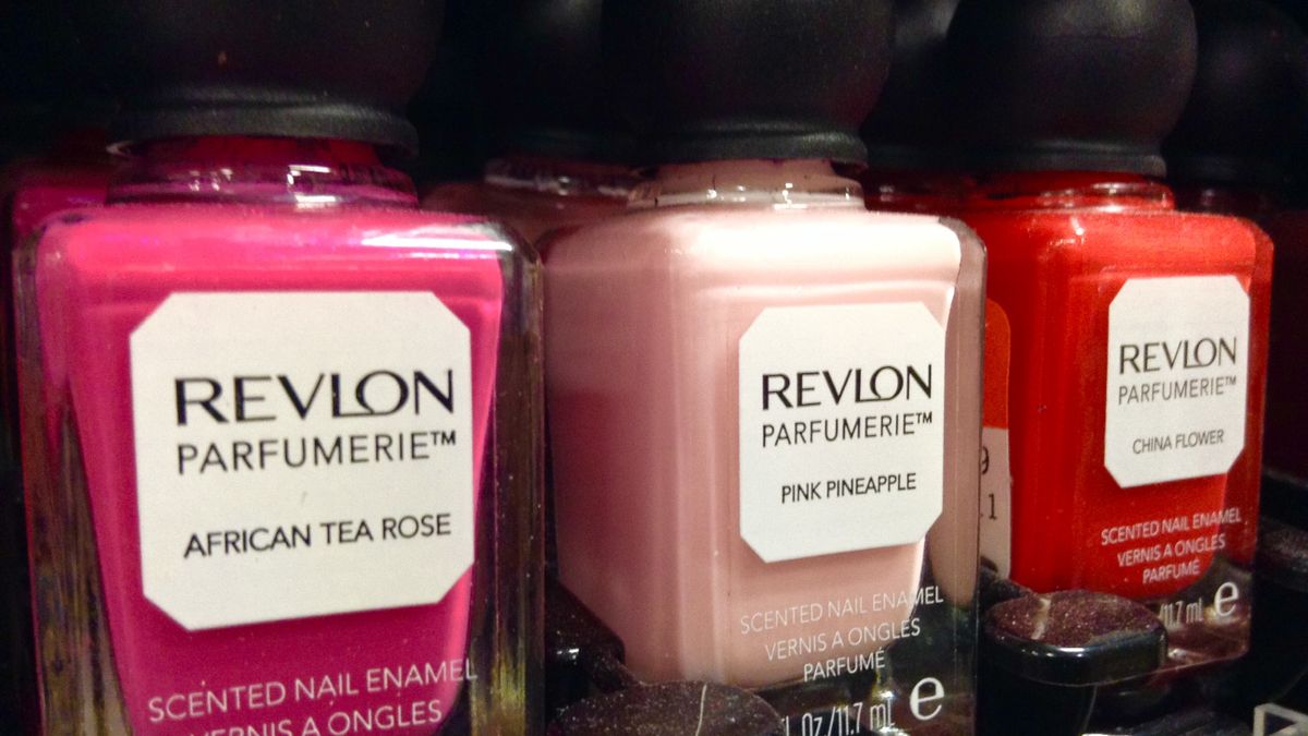 A row of bright pink, pale pink and red jars of Revlon nail polish, with black caps against a black background, in closeup.