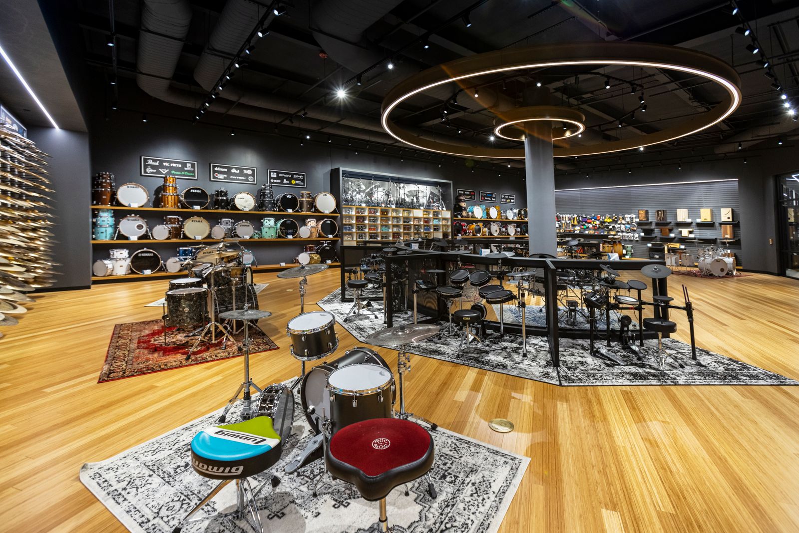 Drum kits and cymbals are displayed in a large open retail showroom