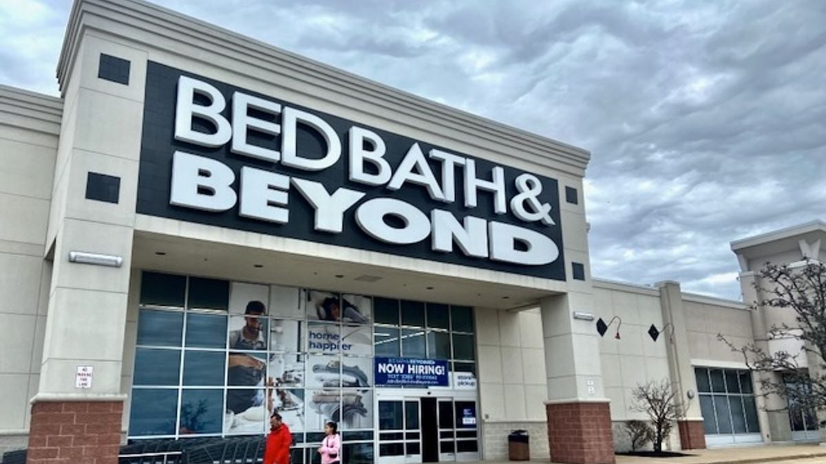 Two people walk by a Bed Bath & Beyond store on a cloudy day.
