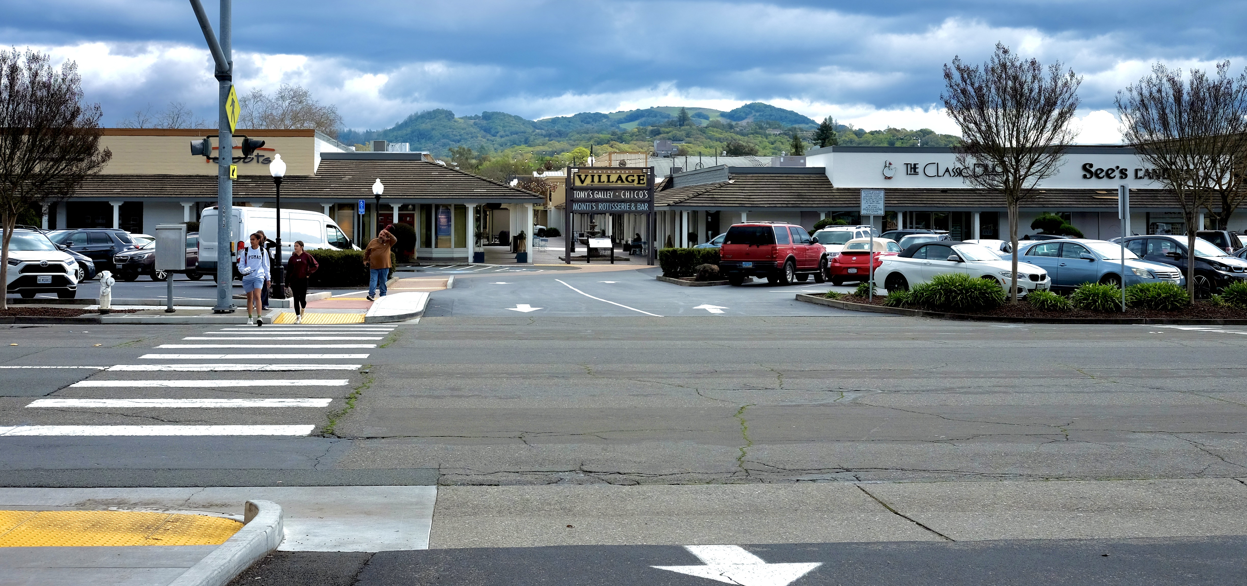 The entrance to an outdoor mall, with mountains in the background and a crosswalk to the left.