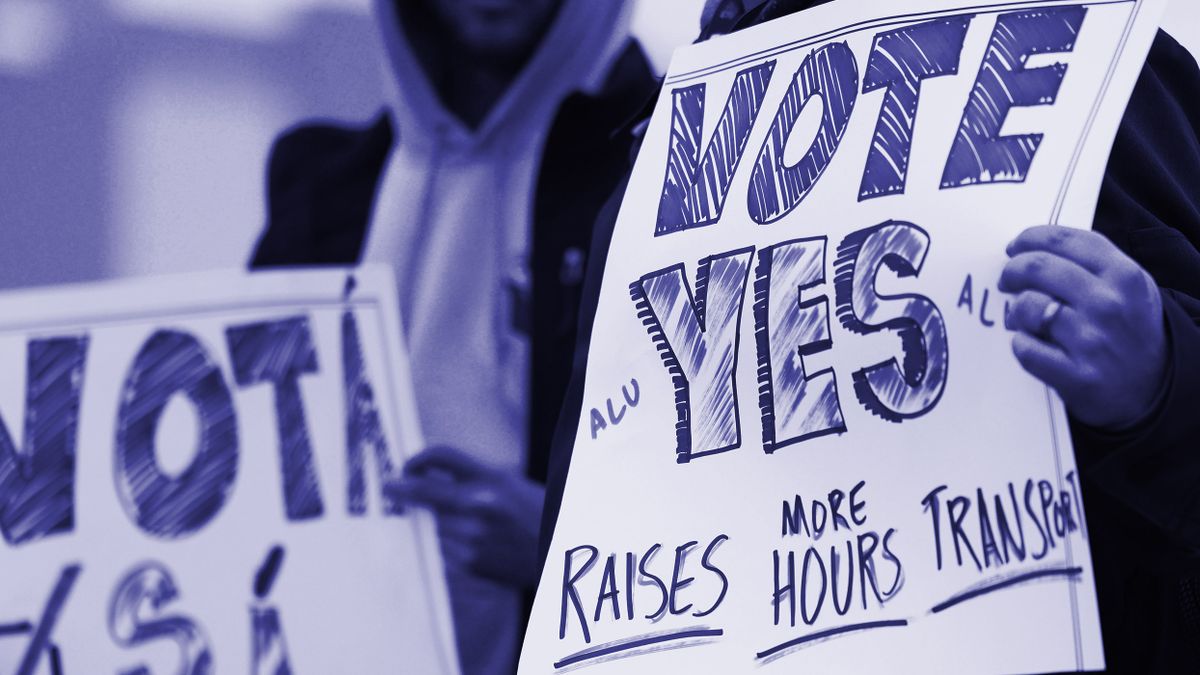 Protestors hold signs that read "Vote Yes - Raises, More Hours, Transport."